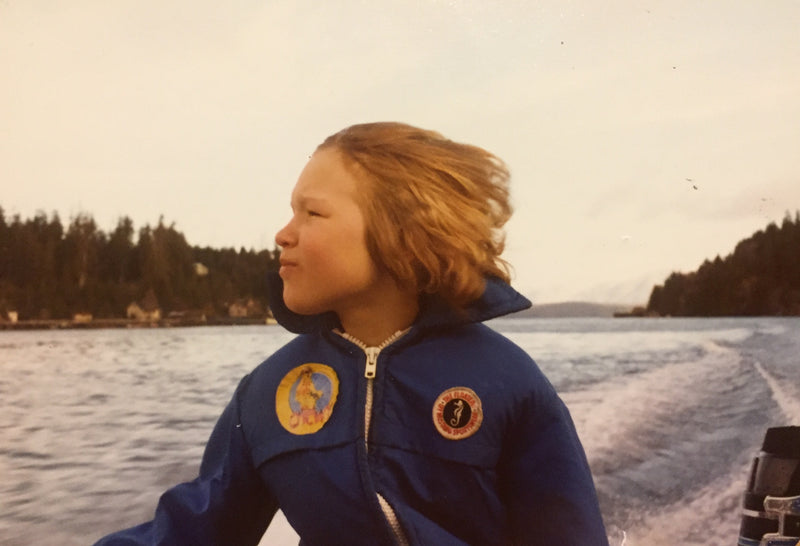 Kid wearing a blue flotation jacket on a boat on a lake