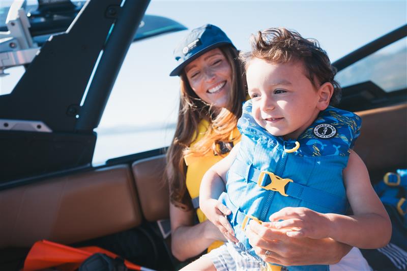 Woman holding a child wearing a life jacket on a boat