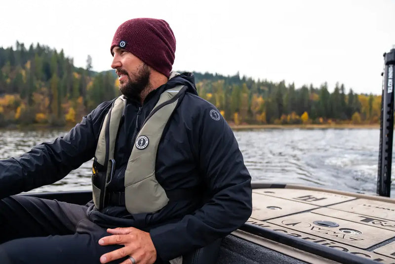 Mustang Survival Ambassador Carl Jocumsen operating a boat on open water, wearing the Elite 120 inflatable PFD.