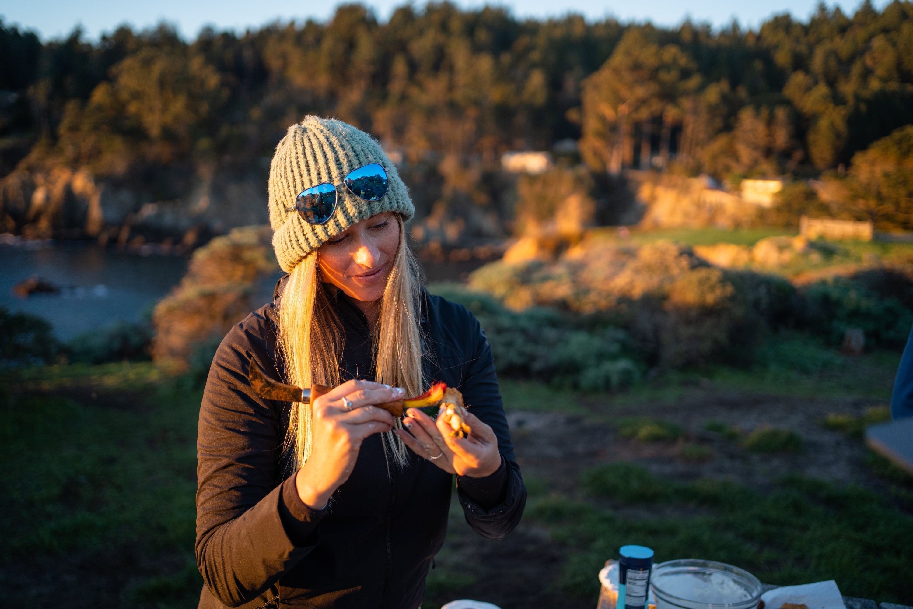 Kayak angler Annie Nagel cleans freshly harvested seafood with a small knife while outdoors during golden hour.