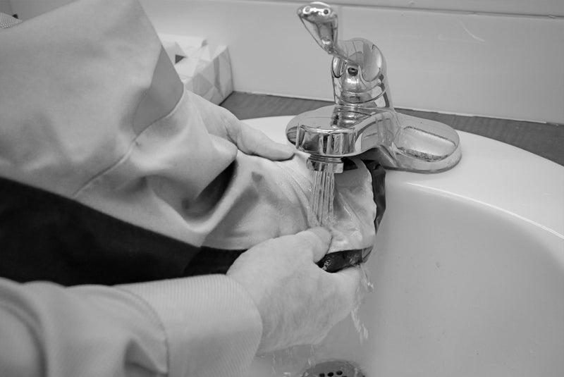 Rinsing a previously stained flotation coat under cold after spot cleaning it with dish soap and then hanging to dry