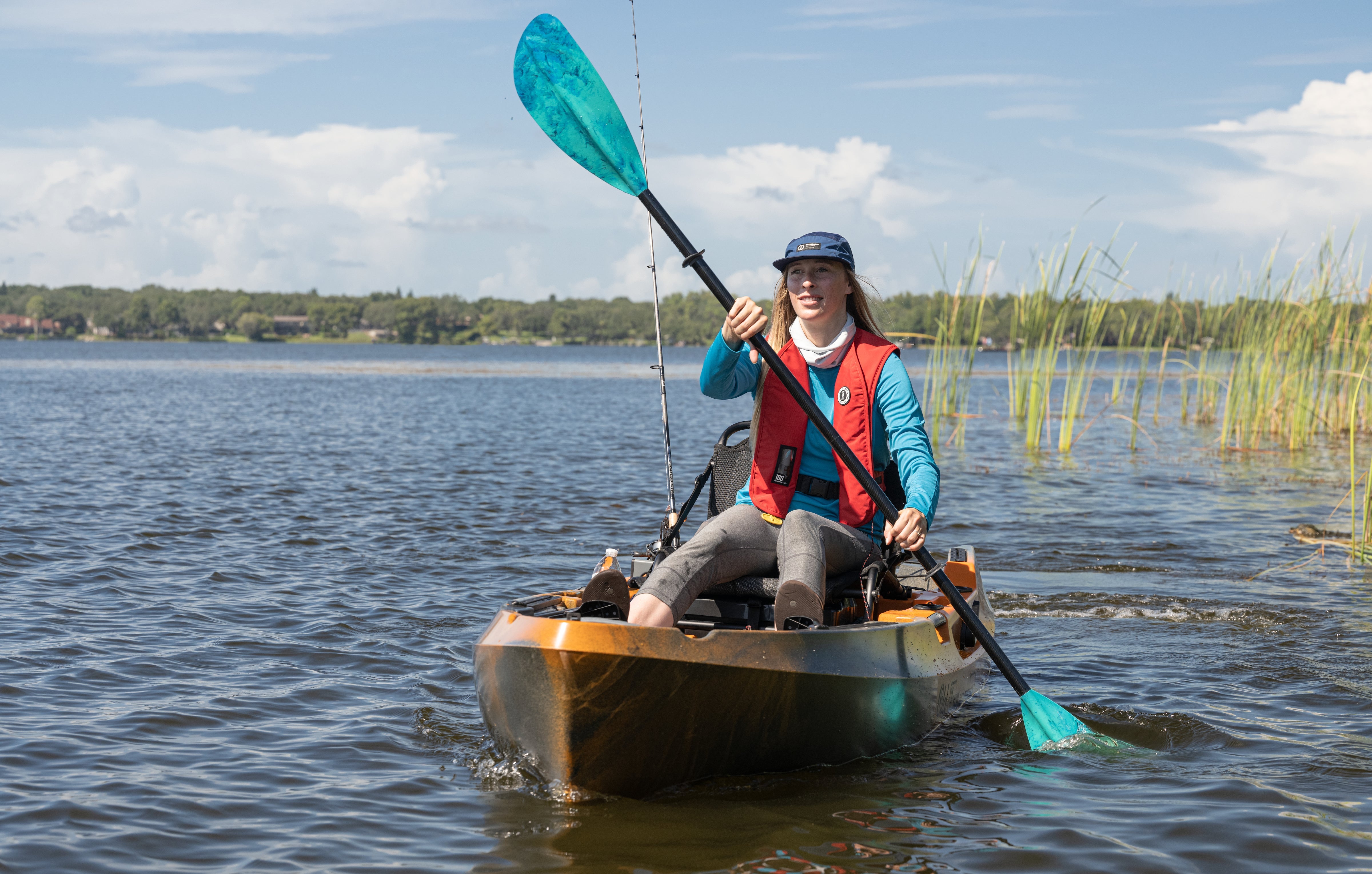 Person kayaking on calm water wearing a red Mustang Survival MIT 70 Inflatable PFD, showcasing lightweight comfort and reliable safety for paddle adventures.
