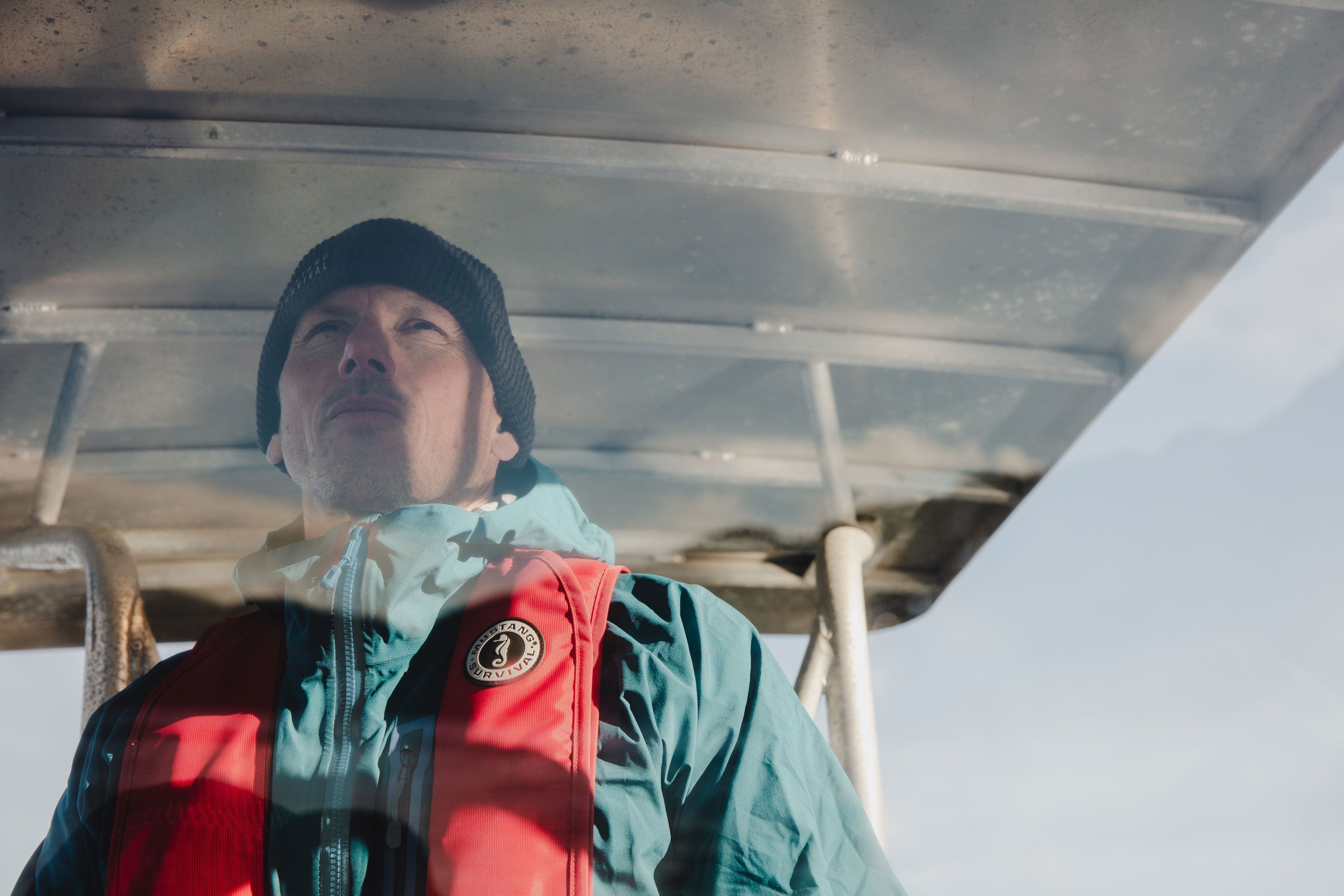 Person boating in Howe Sound wearing a red Mustang Survival MIT 100 Inflatable PFD, showcasing lightweight design and reliable on-water protection.