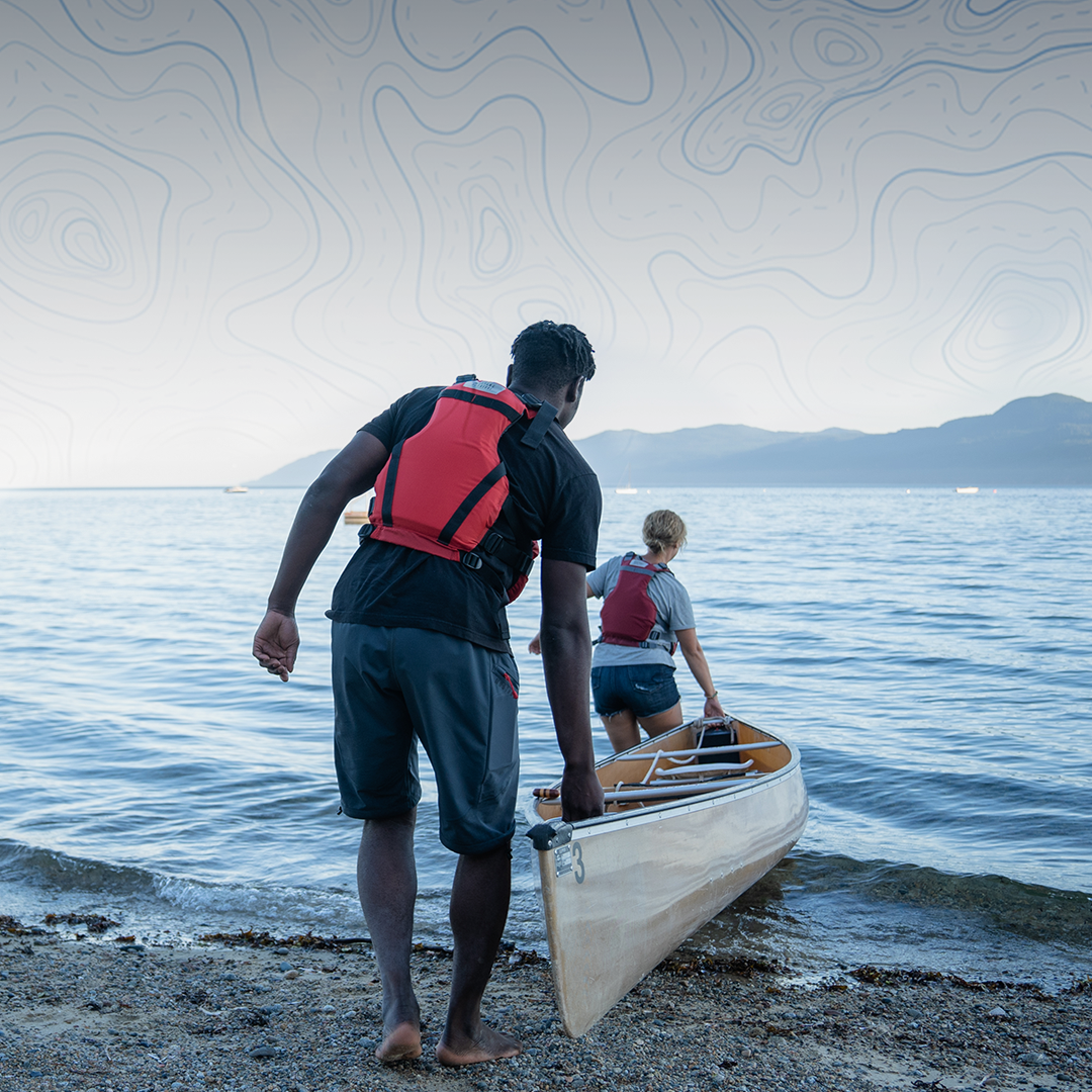 inshore sailboat with 2 people paddleboarding near the shore