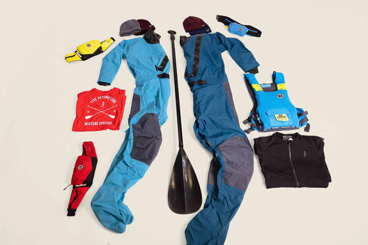Mustang Survival dry suits and accessories laid out for holiday gifts for paddlers, featuring Quadra suits and PFDs.