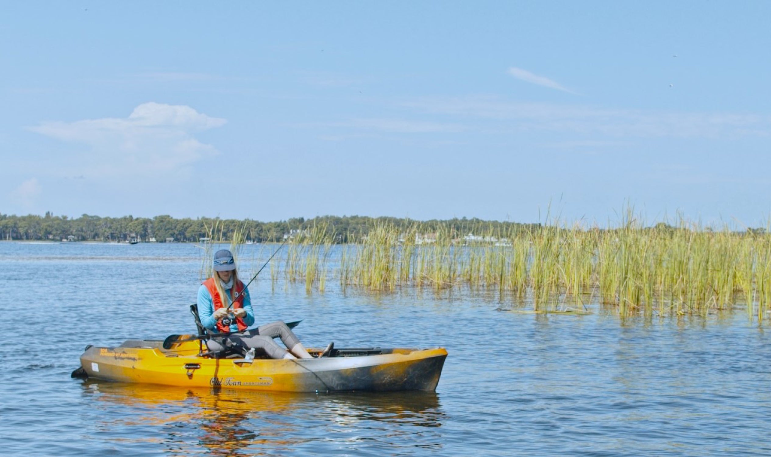 Person fishing from a yellow kayak wearing a Mustang Survival MIT 70 Auto Manual PFD, highlighting its lightweight design and reliable inshore protection.